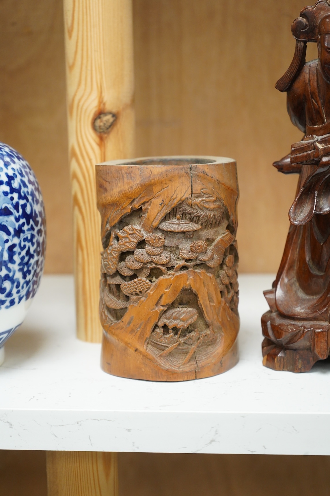 A bronzed Chinese figure of Qianlong, a carved bamboo brush pot and a hardwood figure, largest 20cm high